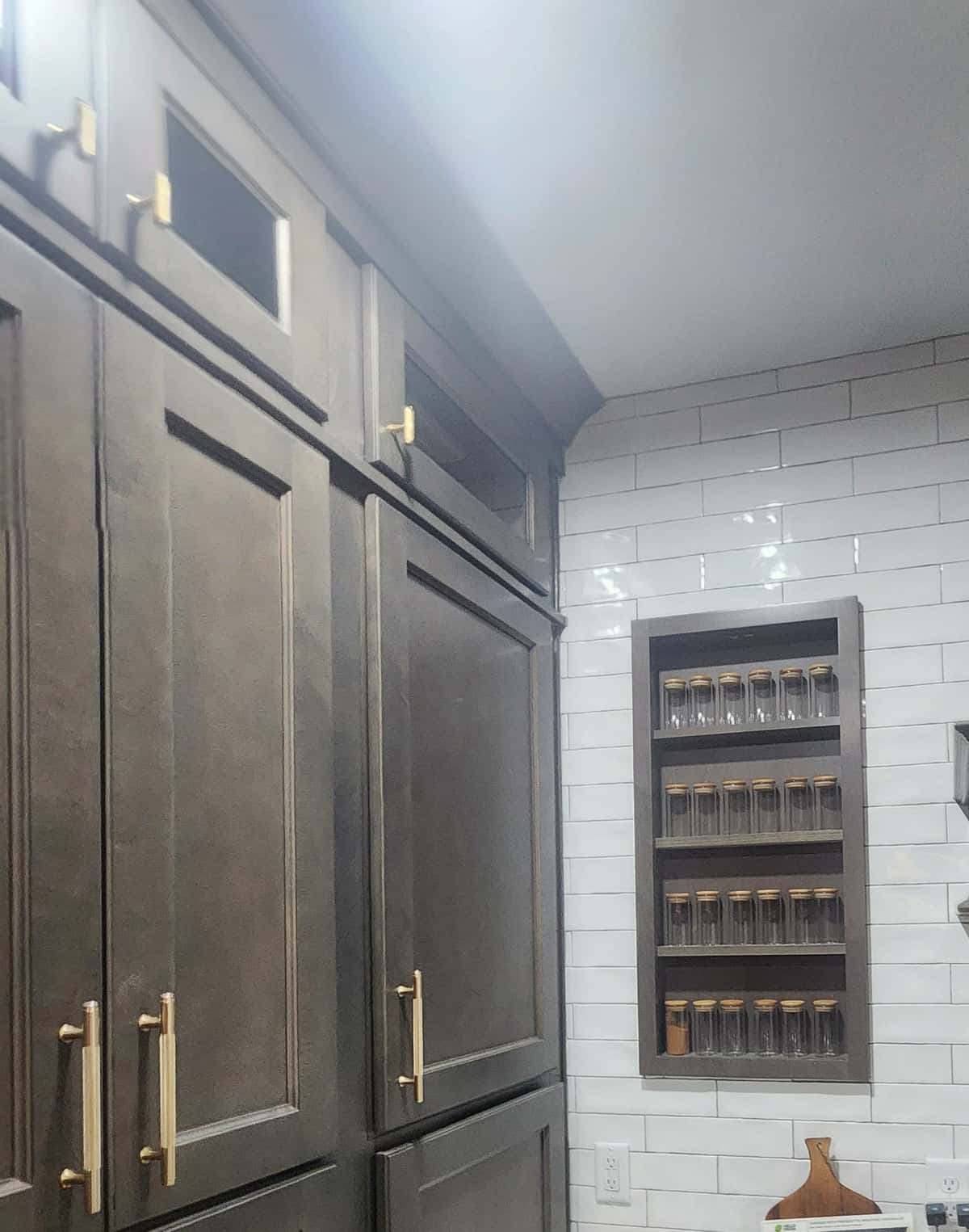 Built-in recessed spice niche beside tall espresso cabinetry with brushed brass pulls