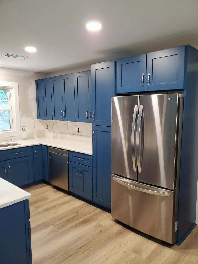 Navy shaker cabinetry wall with integrated refrigerator surround and white quartz countertops