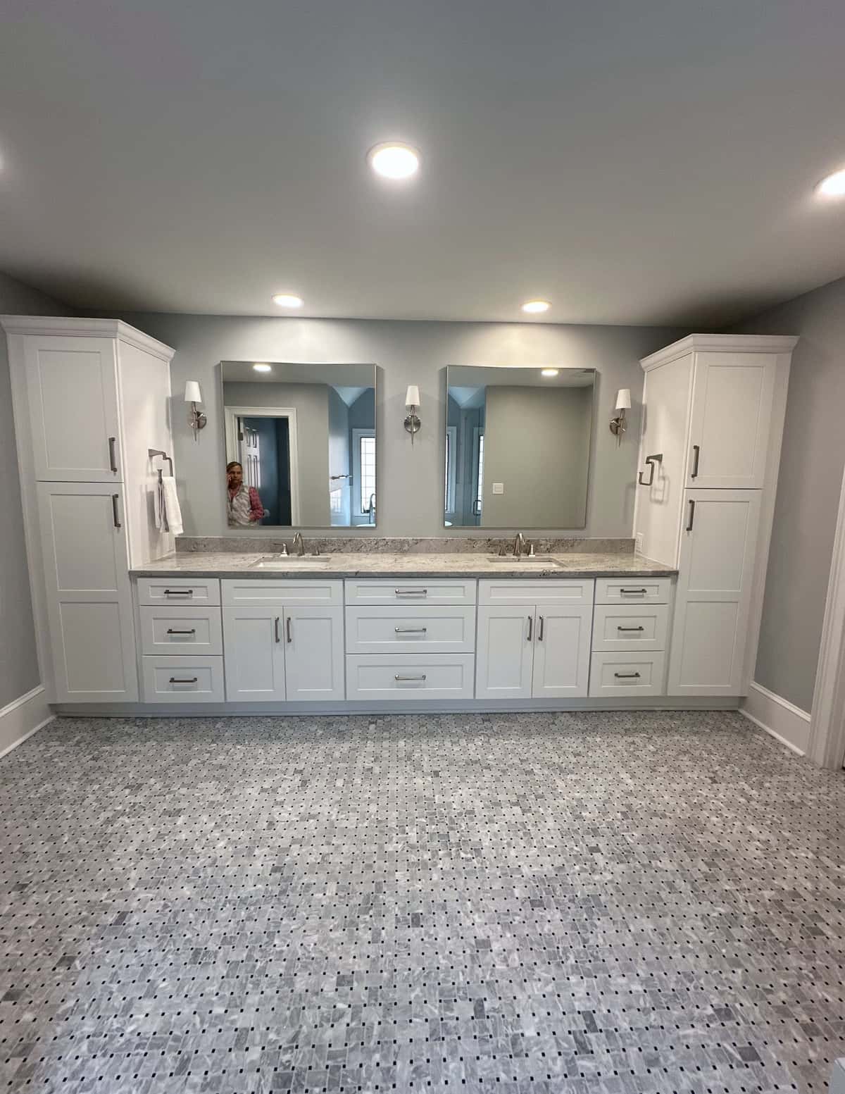Long white shaker double vanity with linen towers, framed mirrors and a basketweave marble mosaic floor